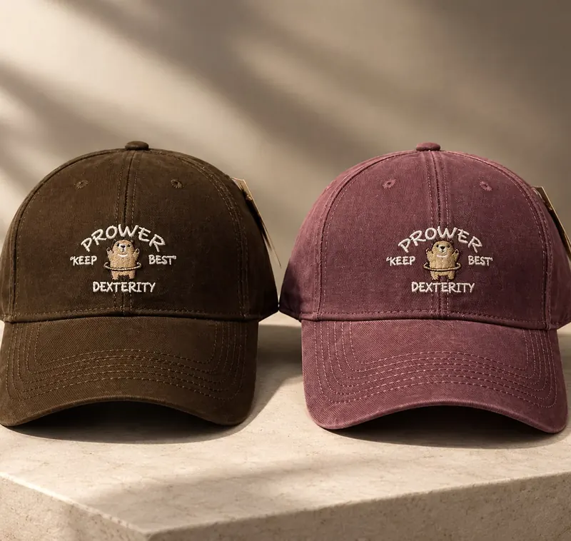 Two Prower dad caps, one brown and one burgundy, with cream bear embroidery